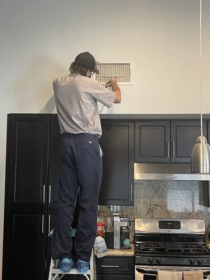 Technician inspecting an air vent during HVAC service in Cedar Hills
